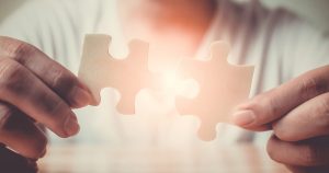 Man holding out two puzzle pieces