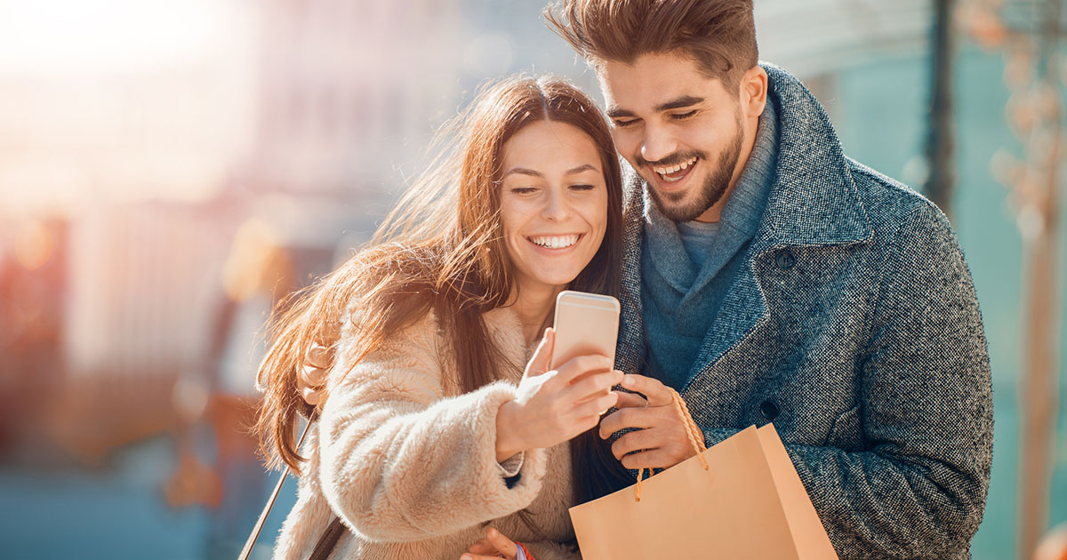 Man and woman looking at a phone while shopping together