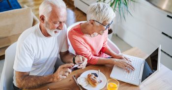 Boomer couple having breakfast, using laptop